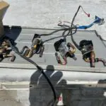 Person in a yellow vest and white hard hat working at a rooftop unit