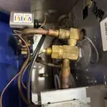 Insulated refrigeration pipes and a blue component on a white wall