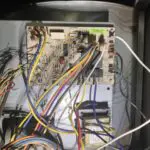 White defrost timer mounted on a metal panel