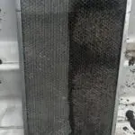 Stack of pleated air filters in front of an outdoor unit