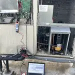 Cylindrical compressor with copper pipes sitting on concrete
