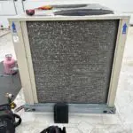 Rooftop HVAC unit on a gravel roof next to a brick wall