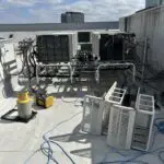 Several gray rooftop HVAC units lined up on a flat roof